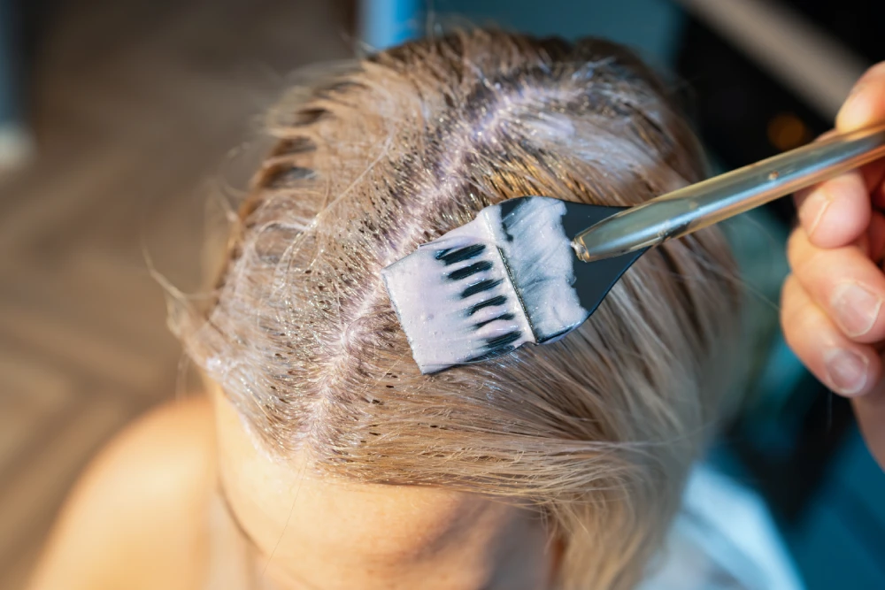 Root touch-ups being applied to hair using a brush.