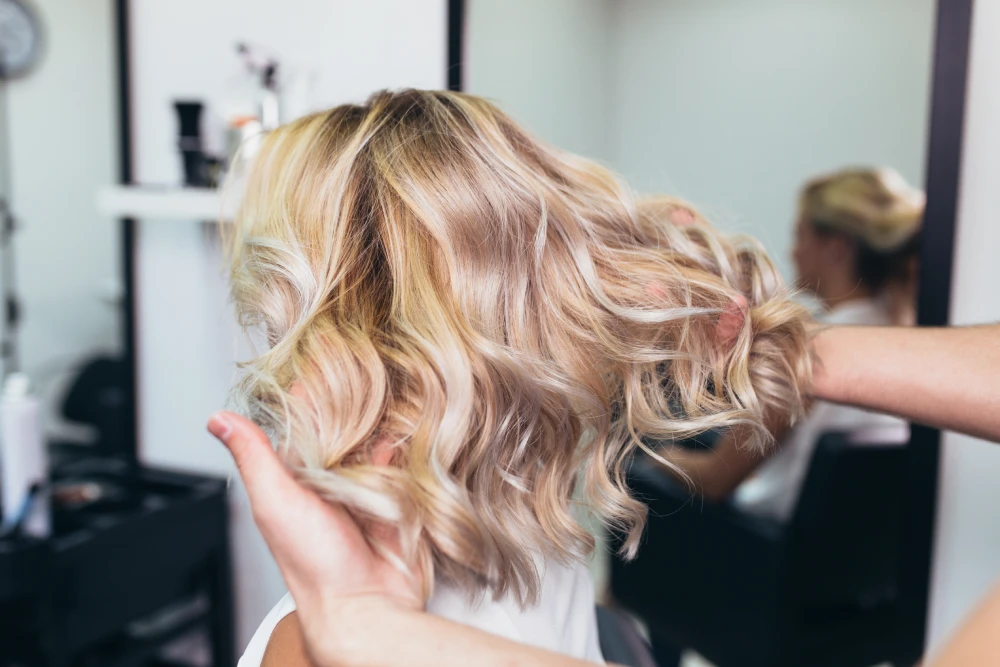 Freshly styled blonde hair with visible highlights in a salon.