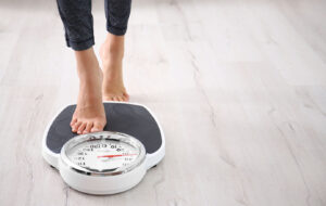 Bare feet stepping onto a scale to track progress during a medical weight loss journey.