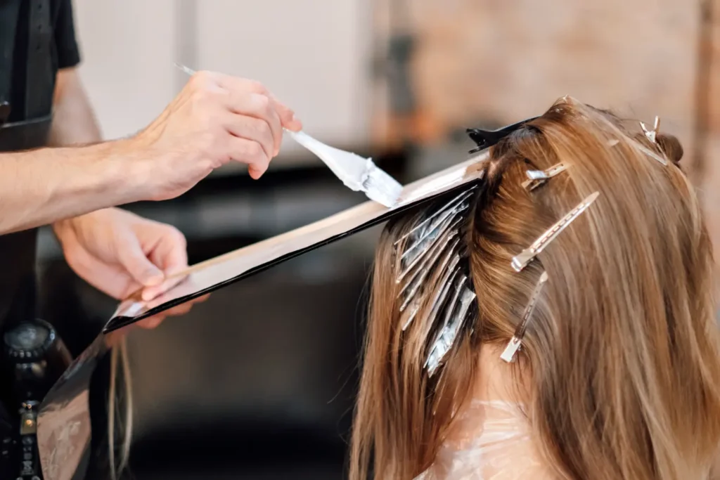 stylist applying balayage highlights with foils in salon