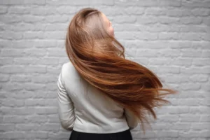 woman flipping long smooth shiny hair showing volume and length after extensions