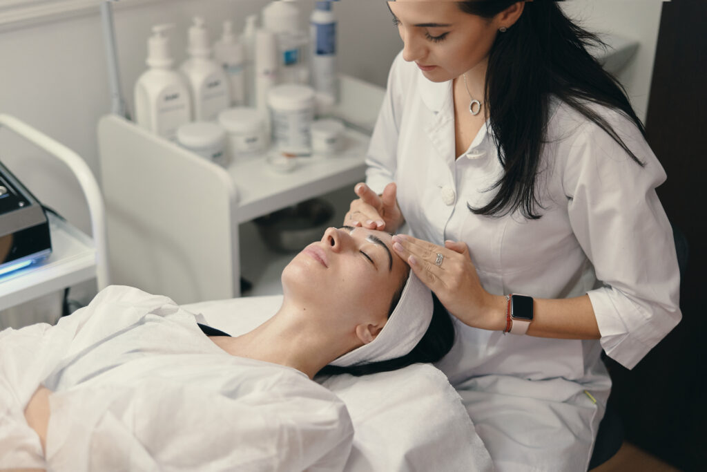 Woman receiving facial treatment while lying down in clinic