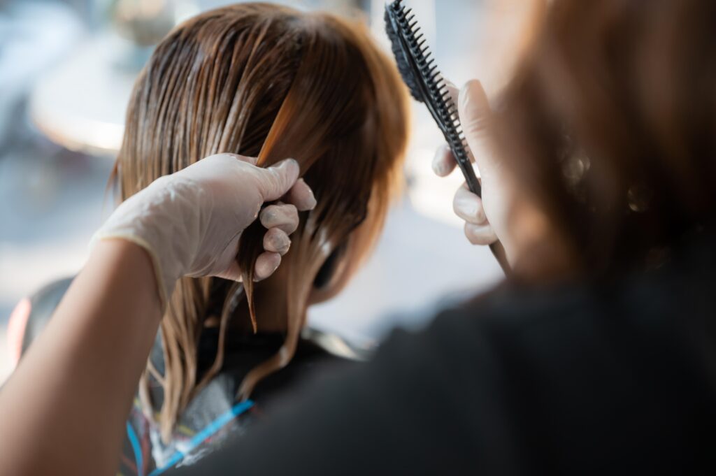 Stylist wearing gloves sectioning and brushing hair during a salon treatment